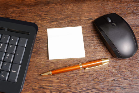 Composition with sticker,  mouse, pen and keyboard laying on wooden desk