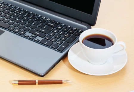 Work office desk with a cup of coffee,  laptop,  penの写真素材