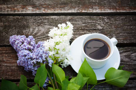 Coffee cup and colorful lilac flowers on wooden backgroundの写真素材