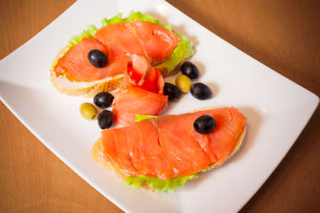 Salmon on a bread with salad and olivesの写真素材