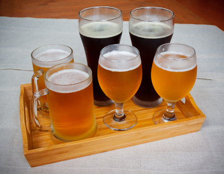 Glasses with different sorts of beer on wooden tray