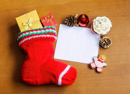 Christmas stocking with card, gifts, sweets and decorations  over wooden  background