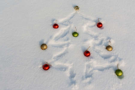 Christmas tree drawn in the snow and adorned with red, golden and green ornamentsの写真素材
