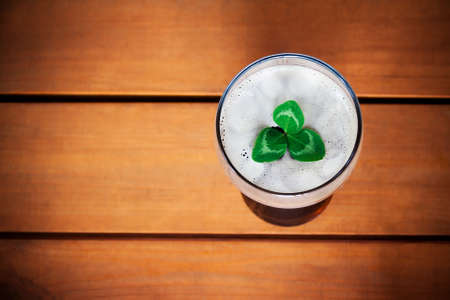 Green shamrock floating on top of glass of dark beer. Selective focus on glassの写真素材