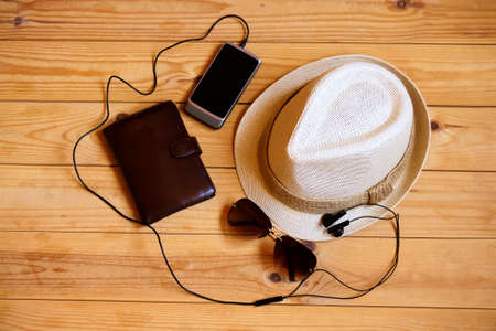 Hat, wallet, smartphone, headphones  and sunglasses on wooden background. Relaxation or vacation conceptの写真素材