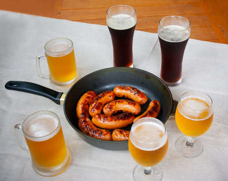 Grilled sausages and beer glasses  on wooden tableの写真素材