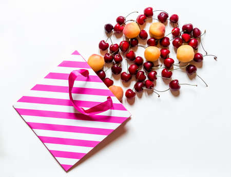 Cherry and apricot fruit in paper bag on beige backgroundの写真素材