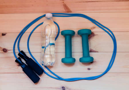 Dumbbells, bottle of water and skipping rope on wooden backgroundの写真素材