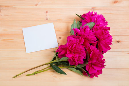 Bunch of peonies and blank card on wooden backgroundの写真素材