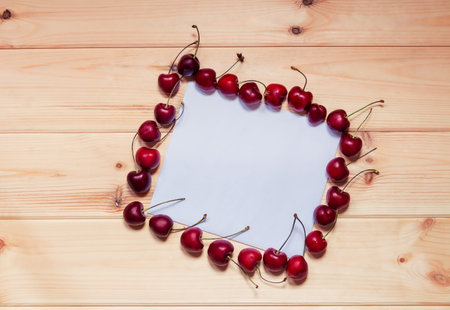 Card for notes with cherries berries on wooden background.