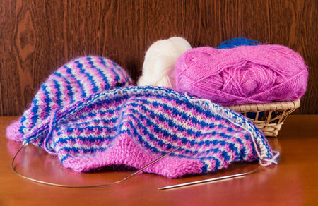 Natural woolen yarn and knitting on wooden background. Selective focus