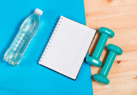 Bottle of  water, notebook and  dumbbells on yoga matの写真素材
