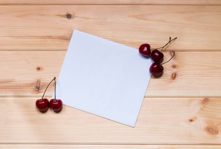 Card for notes with cherries on wooden background.