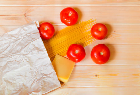 Spaghetti pasta with fresh tomatoes and parmesan cheese in paper bagの写真素材