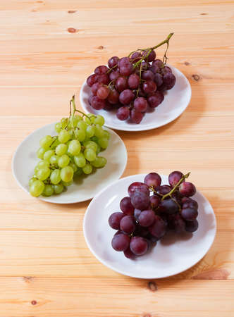 Green  and purple grapes on wooden table.の写真素材