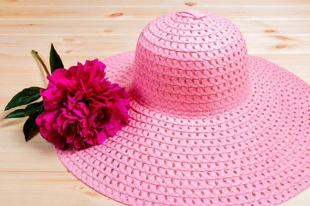 Hat and peony flower on wooden background. Selective focus