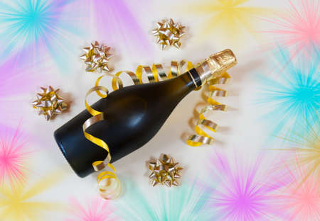 Bottle of champagne on horizontal position, gold ribbon and gold gift bows. Beige backgroundの写真素材