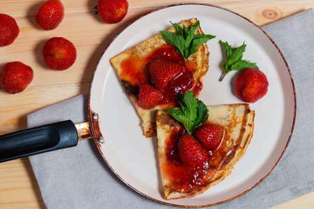 Crepes with fresh strawberries and jam in frying panの写真素材