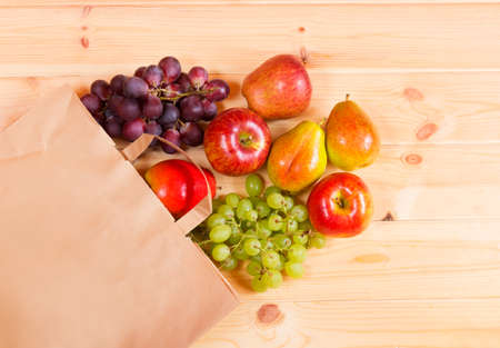 Fruits are rolled out of paper bag to wooden backgroundの写真素材
