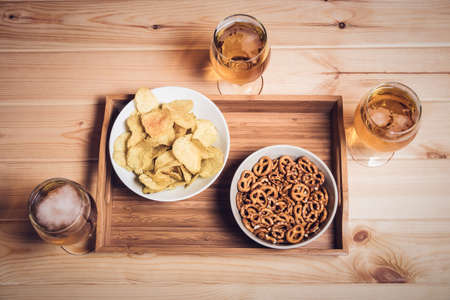 Beer glasses and beer snacks on wooden table. Drink and snack for football match or party. Vintage styleの写真素材