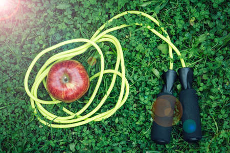 Skipping rope and red apple on grassの写真素材