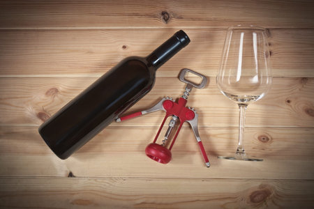 Red wine bottle, empty wine glass and corkscrew on wooden  backgroundの写真素材
