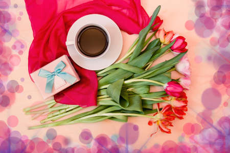 White cup of coffee with tulips and gift box. Top view. の写真素材