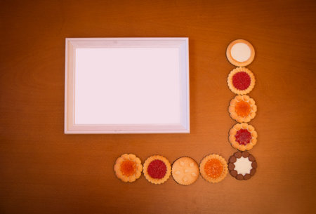 Assortment of mixed biscuits and empty white frame on rustic wooden background. Top view with copy...