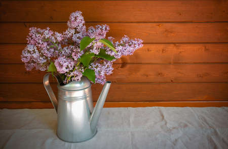 Watering can with branches of lilac flowerの写真素材