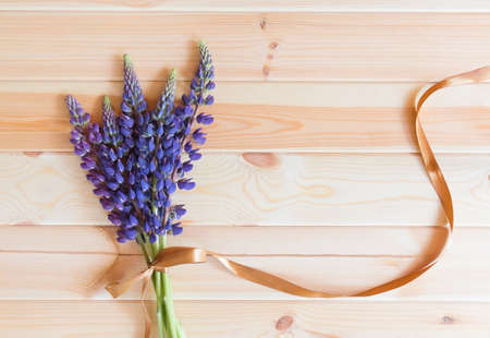 Blue wildflowers lupine with ribbon on wooden background. Top view, copy space.の写真素材