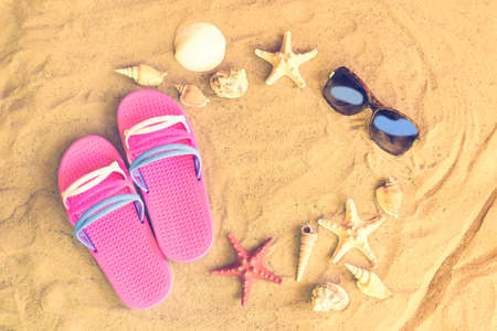 Pink flip fops, sunglasses, starfishes and seashells on sand beachの写真素材
