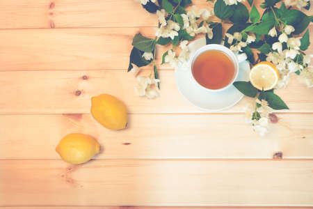 Green tea, lemon and jasmine flowers on wooden background. Top view, copy space. Toned image.の写真素材