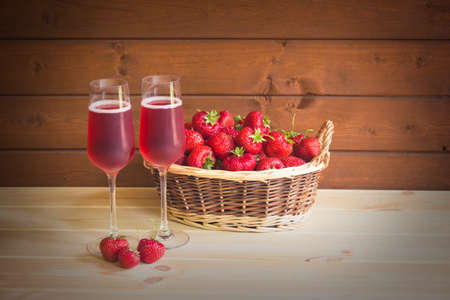Two glasses of rose champagne and fresh strawberry in wicker basketの写真素材
