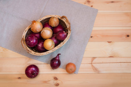 Onions in basket on wooden background. Top view. Copy space.の写真素材