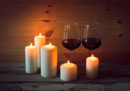 Glasses of red wine with candles on wooden backgroundの写真素材