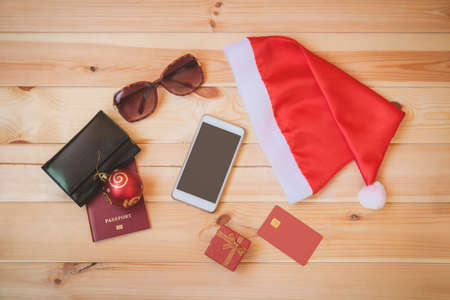 Santa Claus hat and set of things for holidays on wooden background. Christmas travel concept.の写真素材