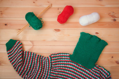 Knitted sweater with knitting needles and wool on wooden background
