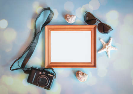 Summer beach holiday concept. Photo frame, photo camera, sunglasses and seashells on blue background.の写真素材