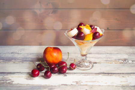 Glass bowl of healthy fruit salad and fruits near. View with copy space.