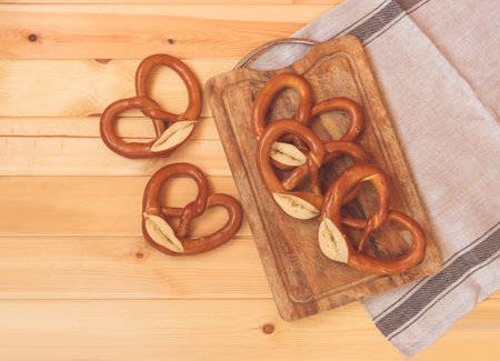 Pretzels on wooden cutting board and near on rustic wooden background. Top view.