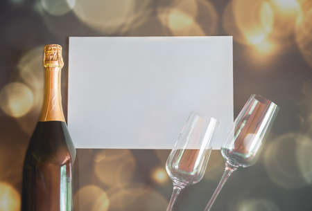 Bottle of champagne and two empty glasses with empty card for your notes.  Dark backgroundの写真素材