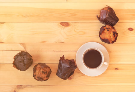 Border made from cup of coffee and muffins on wooden background. Top view, copy space.