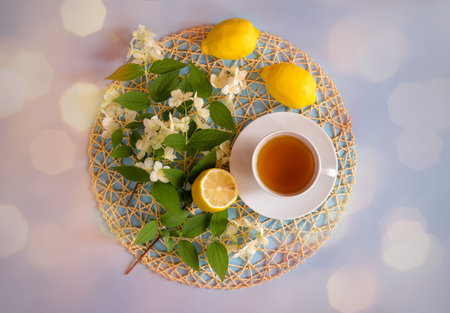 Green tea, lemons and jasmine flowers on blue background. Top view.