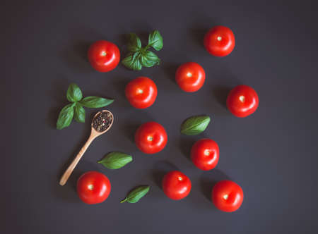 Fresh ripe tomatoes, pepper and green basil leaves on dark background. Top view.の写真素材