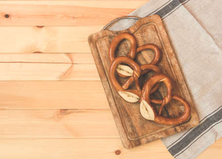 Freshy baked soft pretzels on wooden cutting board on rustic wooden background. Toned image. Top view, copy space.の写真素材