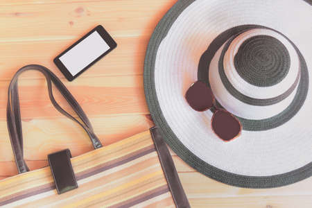Travel accessories. Large summer hat, bag, sunglasses and smartphone prepared for trip. Top view, copy space.の写真素材