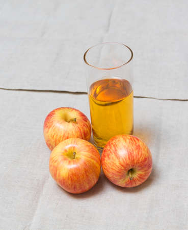 Glass of apple juice and fresh apples near on table.の写真素材