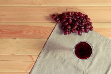 Glass red of wine and red grapes on wooden background. Top view, copy space.の写真素材