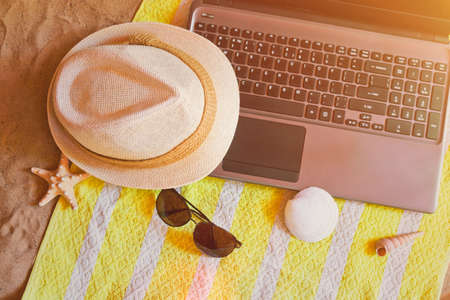 Hat, laptop and sunglasses on towel on sand beach.  View from above.の写真素材
