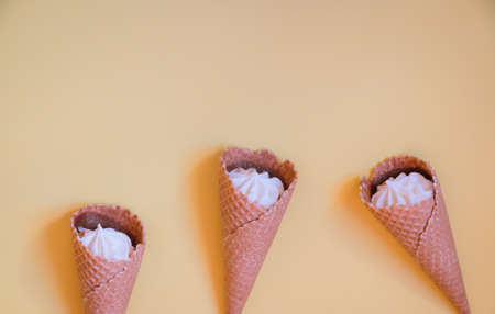 Vanilla ice cream cones on yellow background. Vanilla ice creams in wafer cups.  Top view, copy space.の写真素材